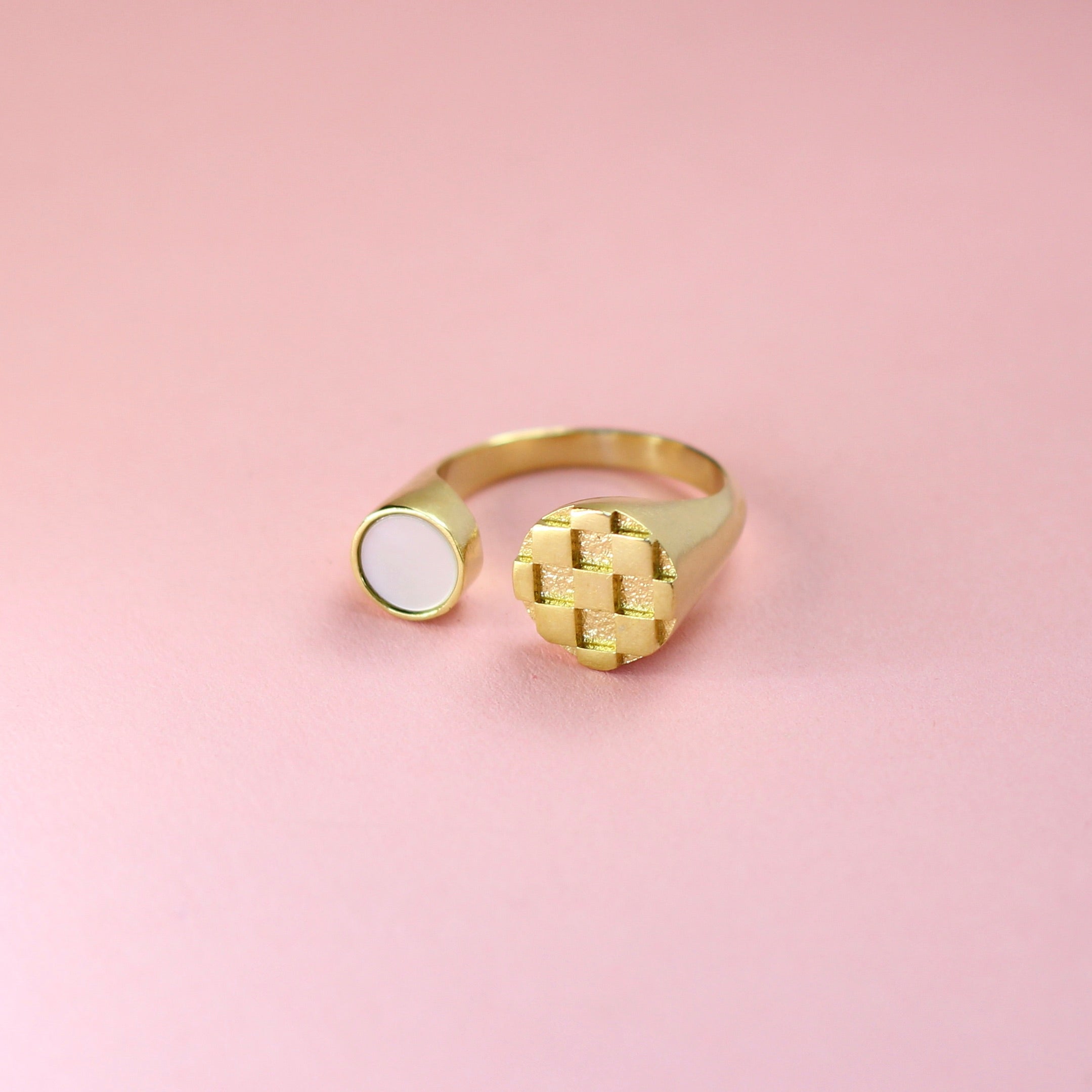 A gold toned bronze ring with a metal checkerboard pattern and mother of pearl inlay