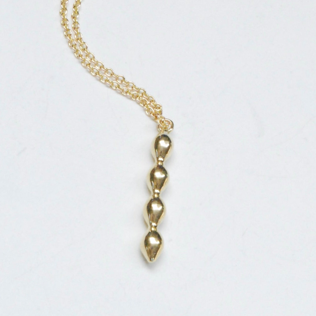 Simple geometric bubble charm on a delicate chain in bronze