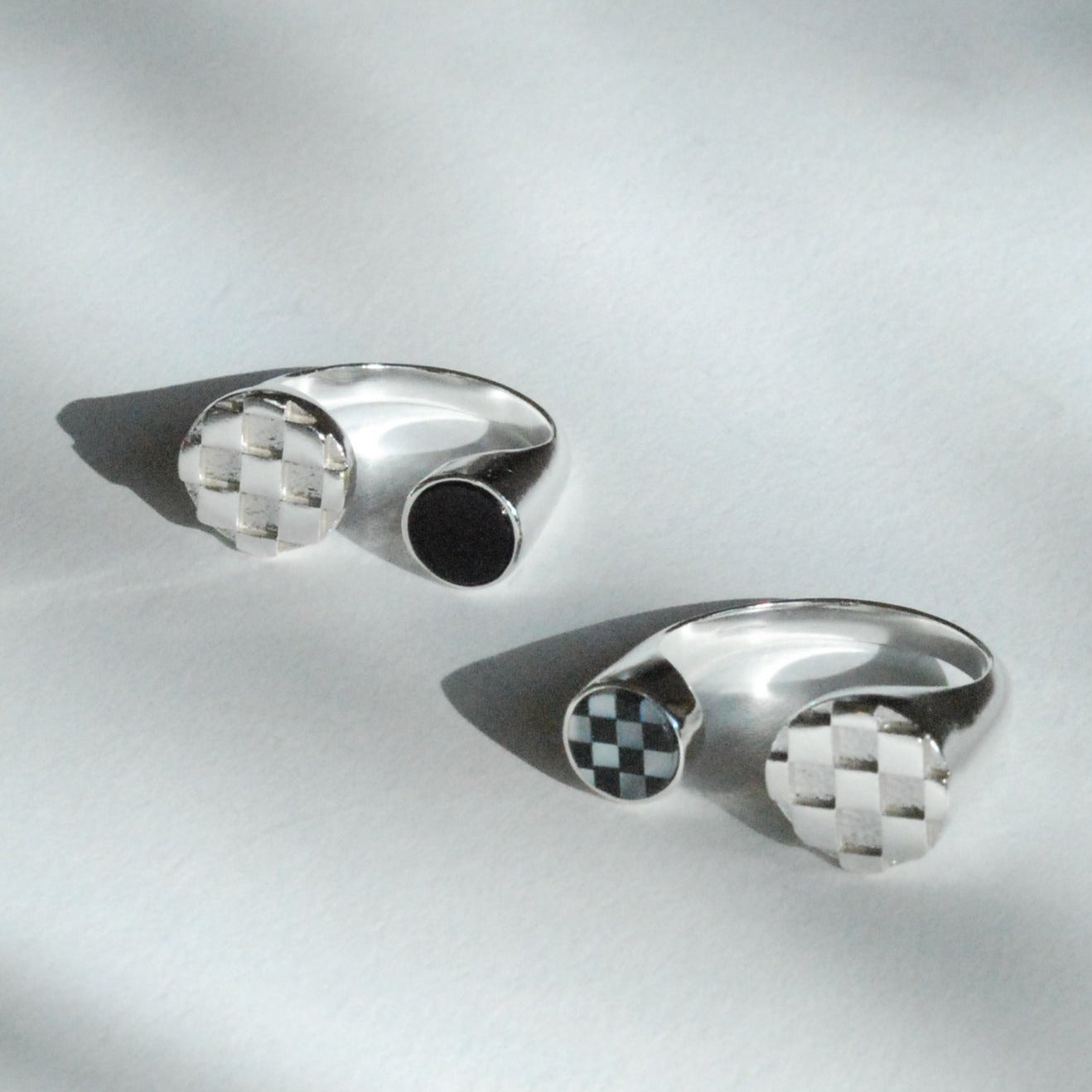Two silver split shank rings with checkerboard on one side and black and white inlay stones on the other