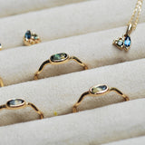 Gold jewelry set with wavy rings and sapphire stones on a beige surface