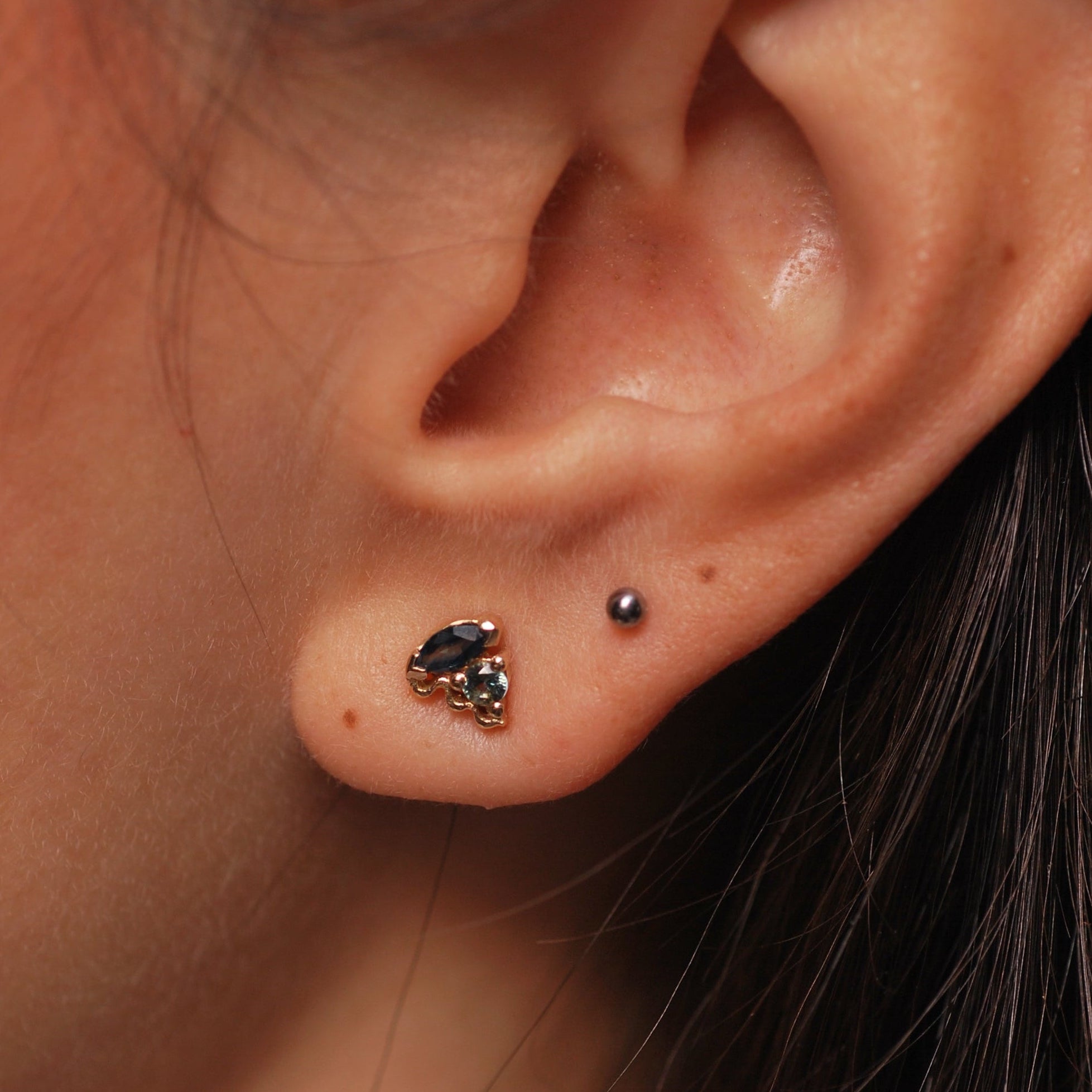 Close-up of an ear with cluster stone earrings with blue stones