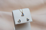 Gold necklace and earrings with blue gemstones on a white stand against a blurred background