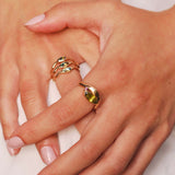 Close-up of hands wearing gold rings on a light background