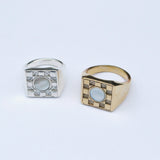 Two square signet rings with a metal checkerboard pattern and white mother of pearl round stone inlays in the center
