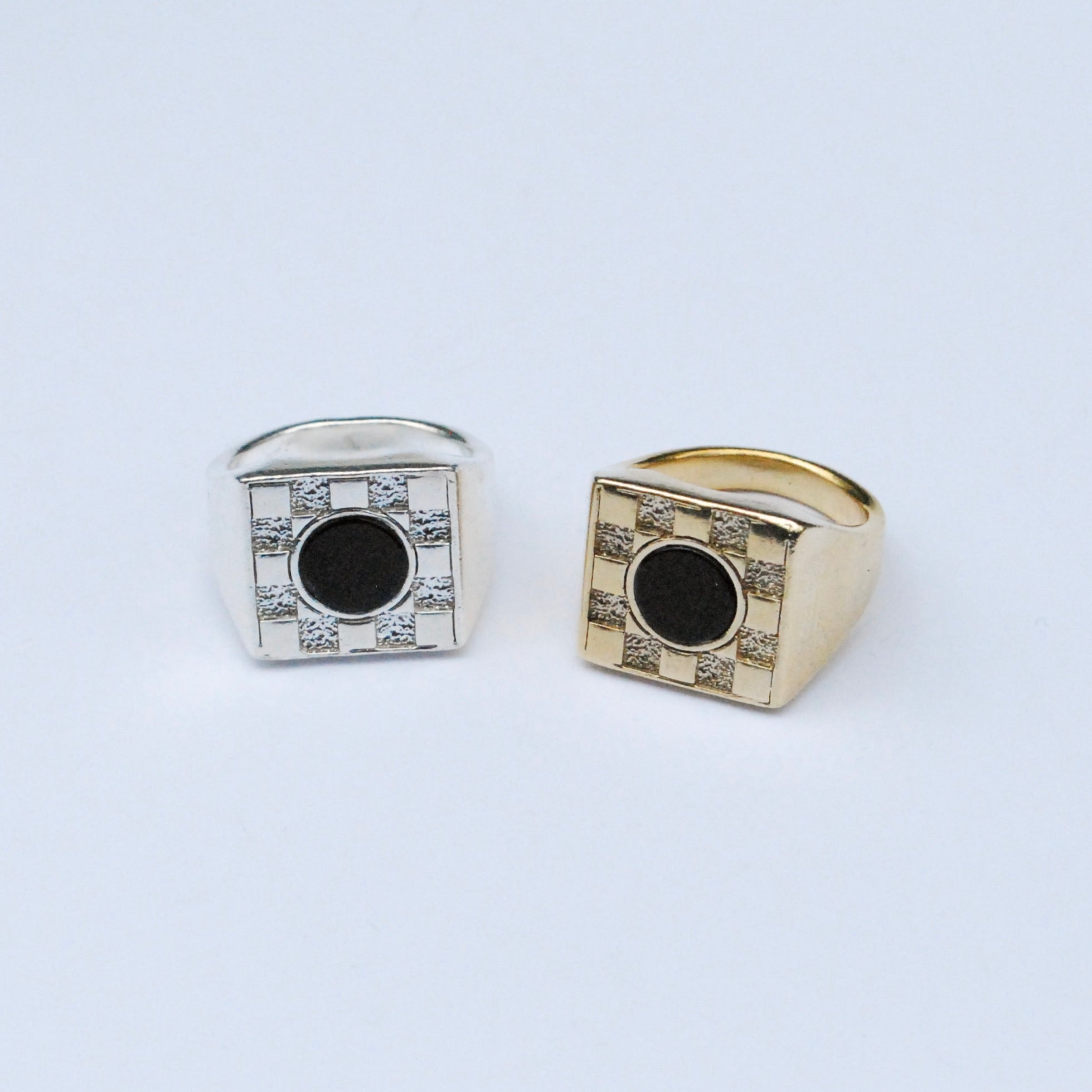Two square signet rings with a metal checkerboard pattern and onyx mother of pearl circle stone inlays in the center