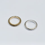 Two rings, one gold-colored and one silver-colored, with a textured, ridged design, displayed against a white background.