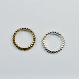 Two ring bands on a grey background, one silver and the other bronze with a repeated geometric pattern