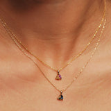 Two gold necklaces with cluster stone pendants on a person's neck.