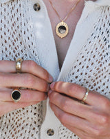 Person wearing three gold rings and a necklace with onyx stones