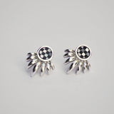 Pair of silver ray earrings with checkered inlay stone on a gray background