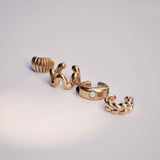 Set of gold colored ear cuffs on a light gray background