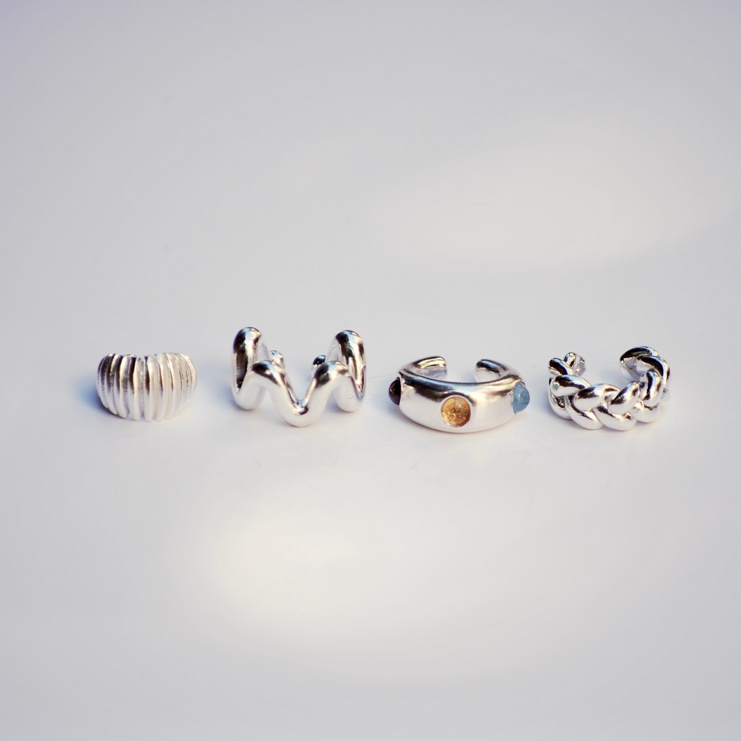 Four silver ear cuffs on a light gray background