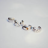 Set of silver ear cuffs on a light gray background