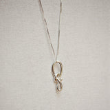 Silver necklace with a unique knot pendant on a light gray background