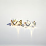 Pair of gold and silver squiggly rings on a light gray background