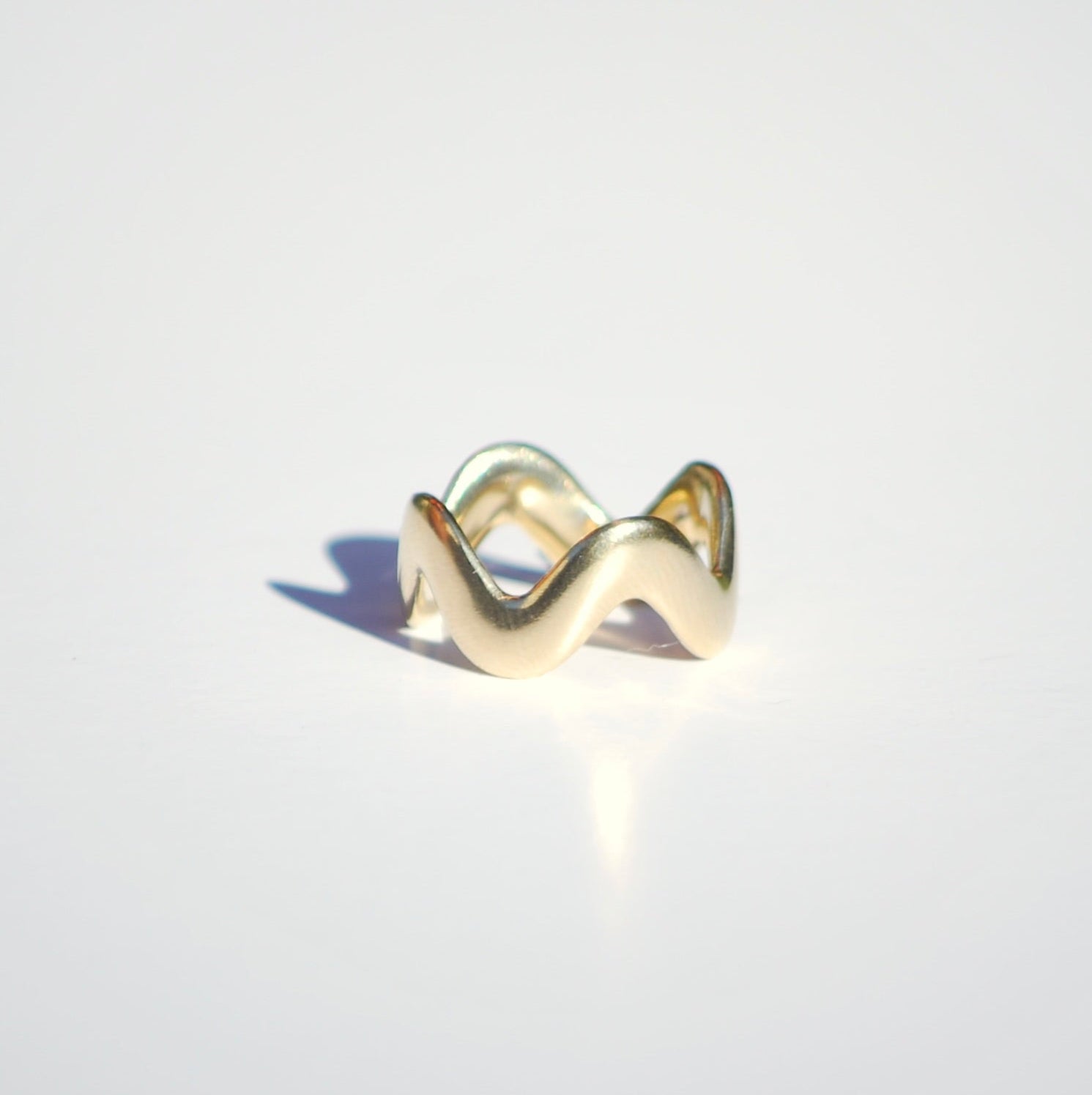 Gold wavy ring on a light gray background
