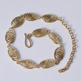 A gold-colored necklace made of spiral parts curled into a spiral on a white background