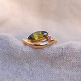 Gold ring with a green gemstone on a textured fabric background