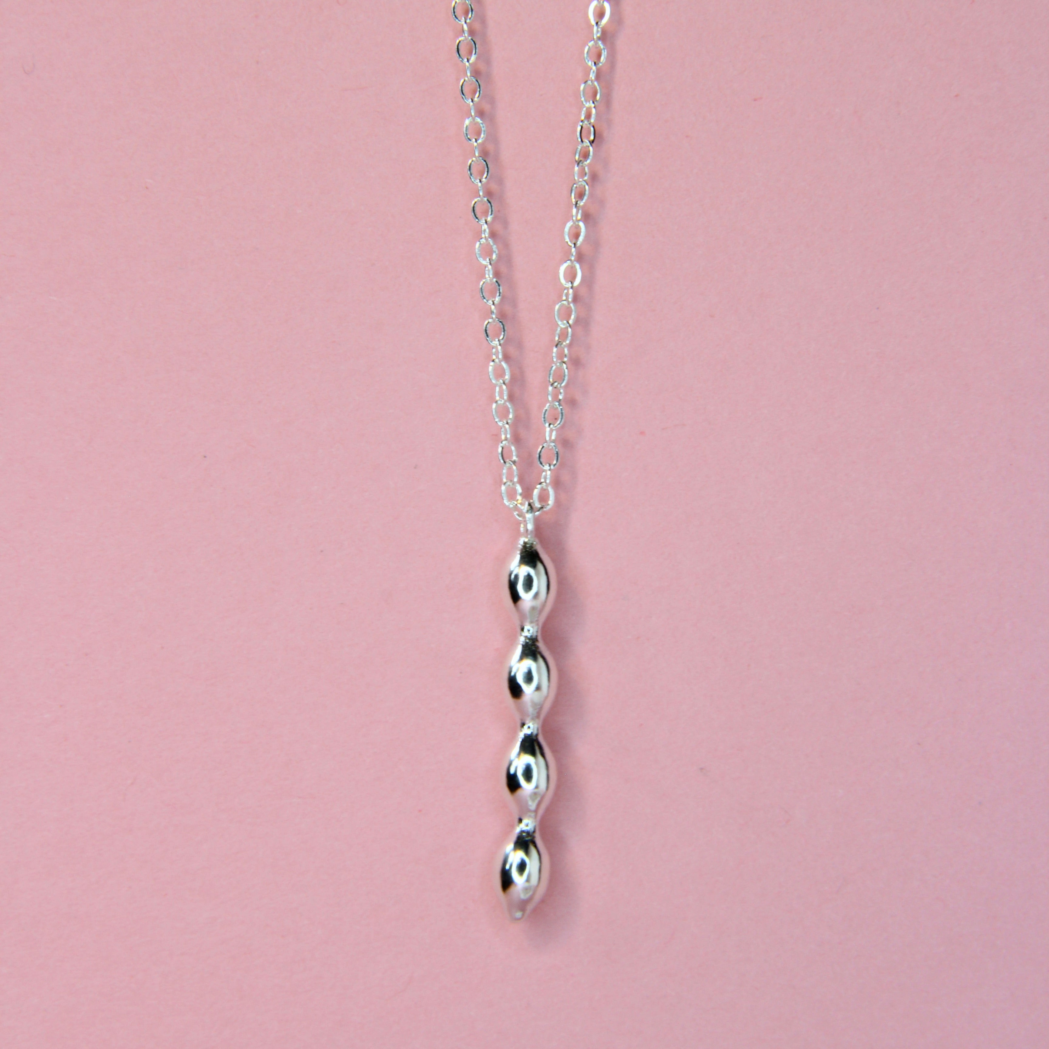 Close up of the bubble charm in silver on a pink background