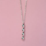 Close up of the bubble charm in silver on a pink background