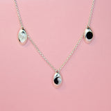 Silver charm necklace with oval pendants with mother of pearl, black onyx, and ying yang inlaid stones.