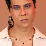 Person wearing delicate huggie hoops in bronze with a round mother of pearl charm