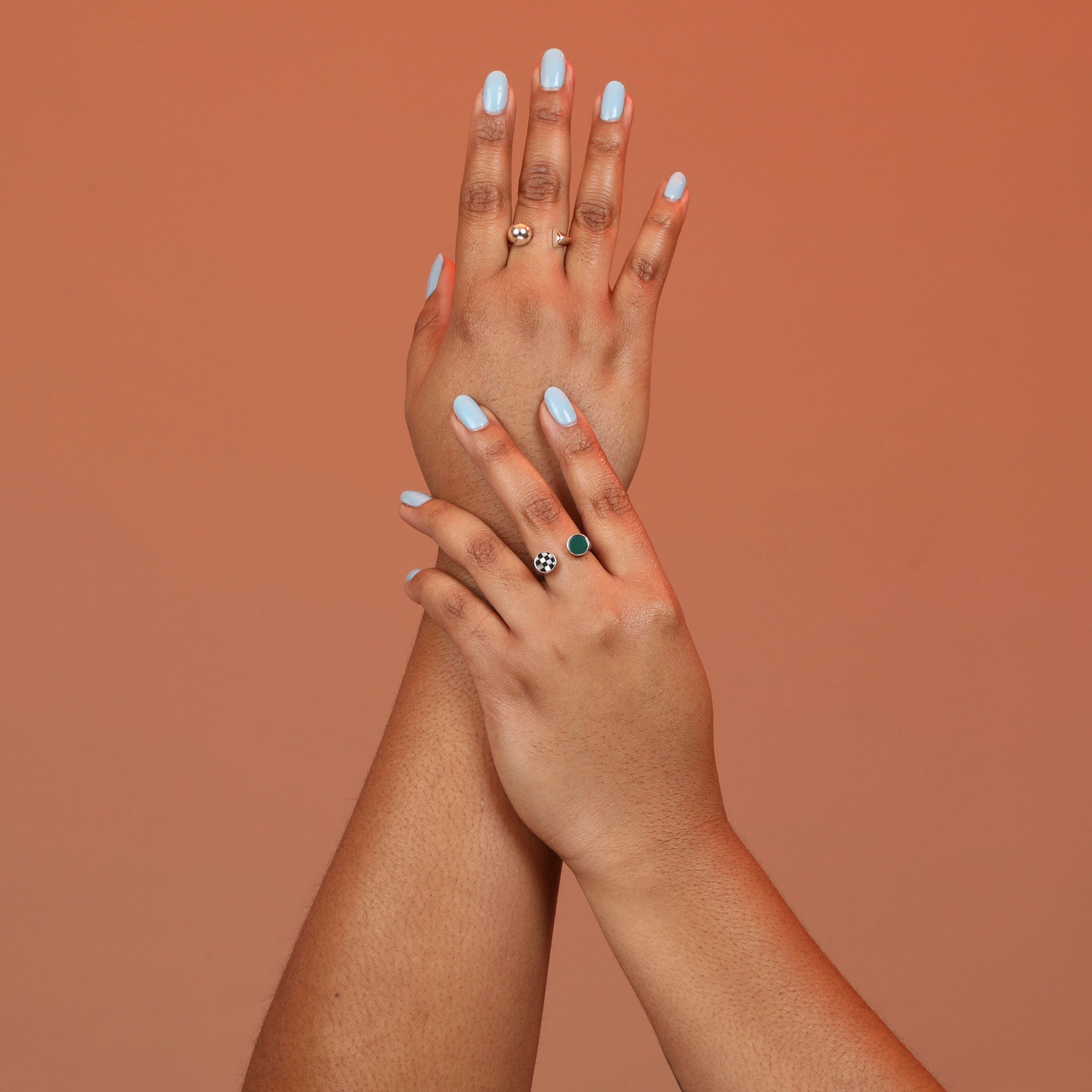 Person wearing two split shank ring designs, one in bronze with two shapes and one with green chrysoprase and checkerboard inlay