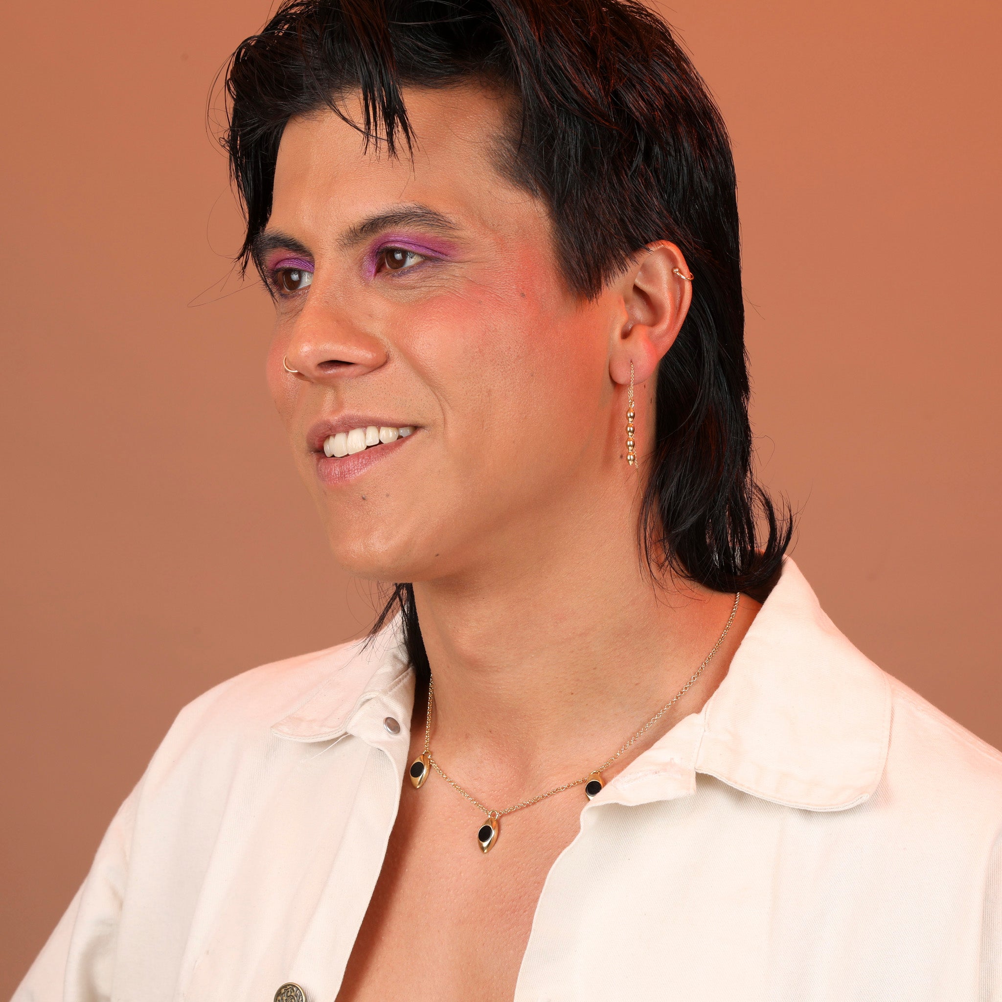 A person wearing gold toned bronze bubble charm threader earrings