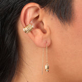 Person wearing a gold toned threader with a geometric charm and a ridged ear cuff