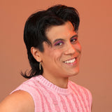 Person wearing bronze huggie hoops with a bubbly pendant charm