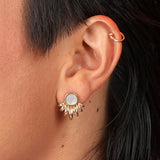Person wearing a bronze sunray shaped earring with white mother of pearl inlay