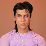 A person wearing silver huggie hoops with geometric charms