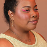 Person wearing a bubble charm in bronze on a delicate chain with matching earrings