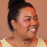 Woman wearing a layered ear stack of huggie hoops and a ribbed ear cuff in gold