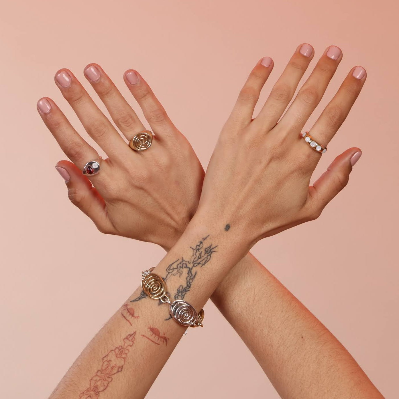 Hands wearing three rings including a gold band with white mother of pearl stones