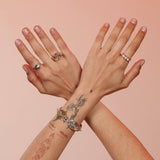 Hands wearing three rings including a gold band with white mother of pearl stones