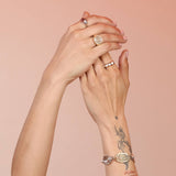 A person's hands showcasing a gold-colored metal spiral signet ring on the ring finger.