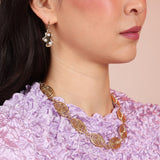 Person wearing art palette earrings and a bronze gold necklace with a spiral pattern