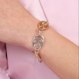 A spiral bracelet made of bronze and sterling silver, worn on a person's wrist.