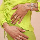 Person showing their hands with a silver spiral bracelet, a bronze squiggly bracelet and two rings