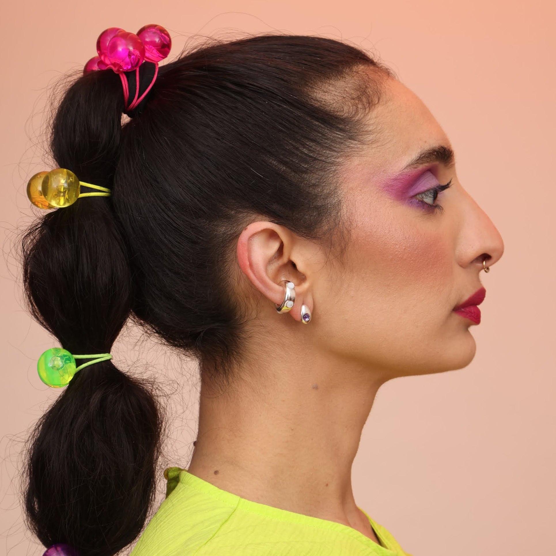A side view of a person wearing a teardrop post in silver and purple with a silver ear cuff with mother of pearl stones