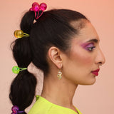 A close-up of a person's face focusing on the earrings, which are colorful and fun