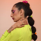 A person wearing an assortment of jewelry with a bronze spiral ring on their pointer finger, a cloud shaped earring, and a spiral bracelet