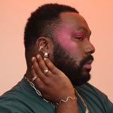 Person wearing a selection of sculptural and colorful gold toned jewelry