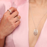 Spiral silver pendant worn with 3 rings