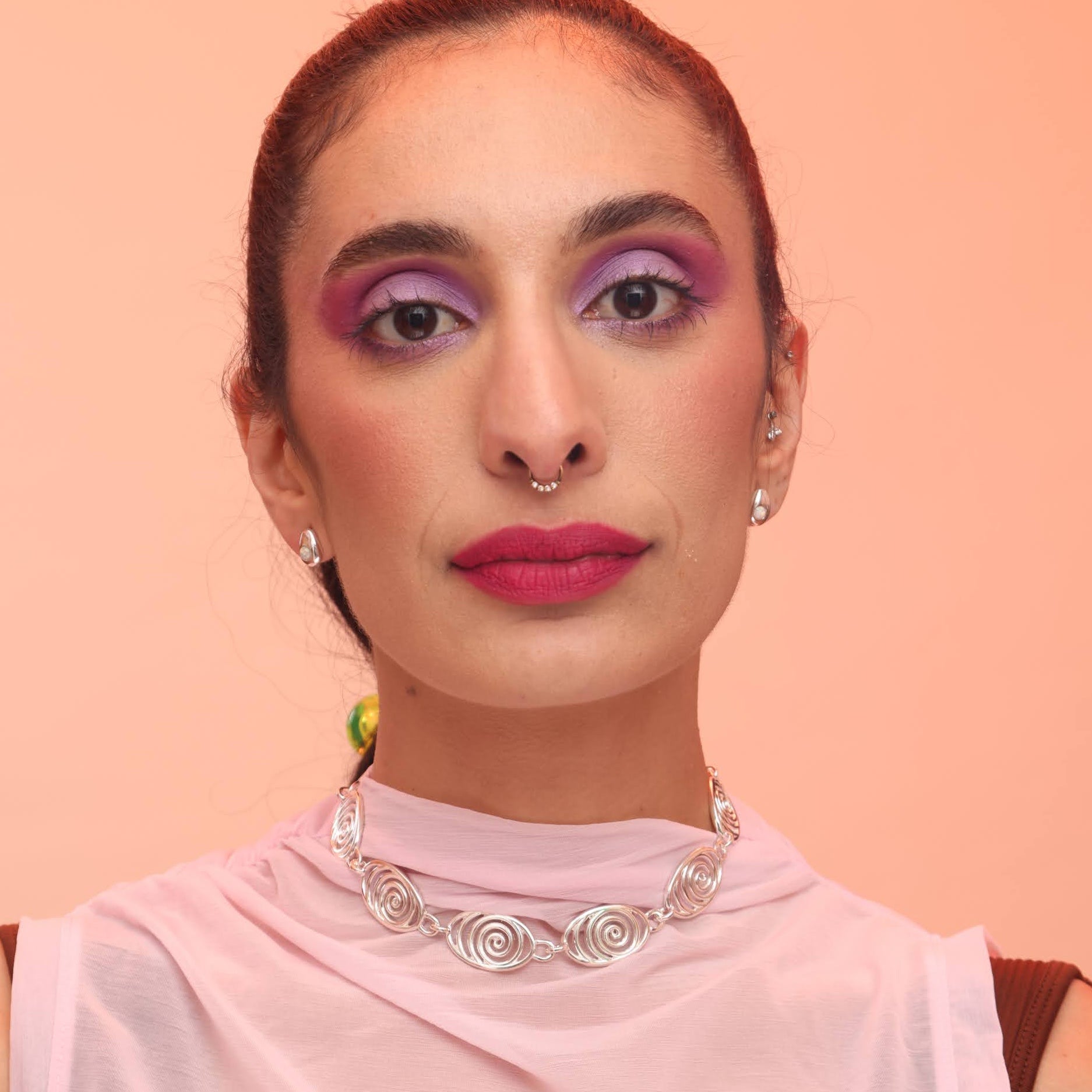 Person wearing dainty teardrop earrings in silver with opal stones and a silver spiral necklace