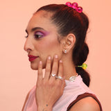 Person wearing silver teardrop earrings, silver rings, and a silver spiral necklace