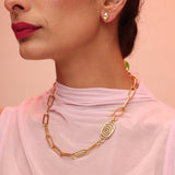 A person wearing a pink top and necklace with a paperclip chain design.