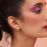 A close up of a person wearing a silver teardrop post earring with a red garnet accent stone