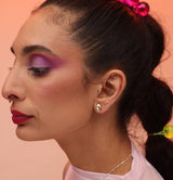 A person wearing a bronze teardrop post earring with an opal stone